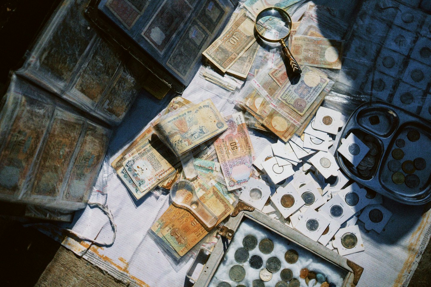 Vintage Indian banknotes and coins arranged with two magnifying glasses.