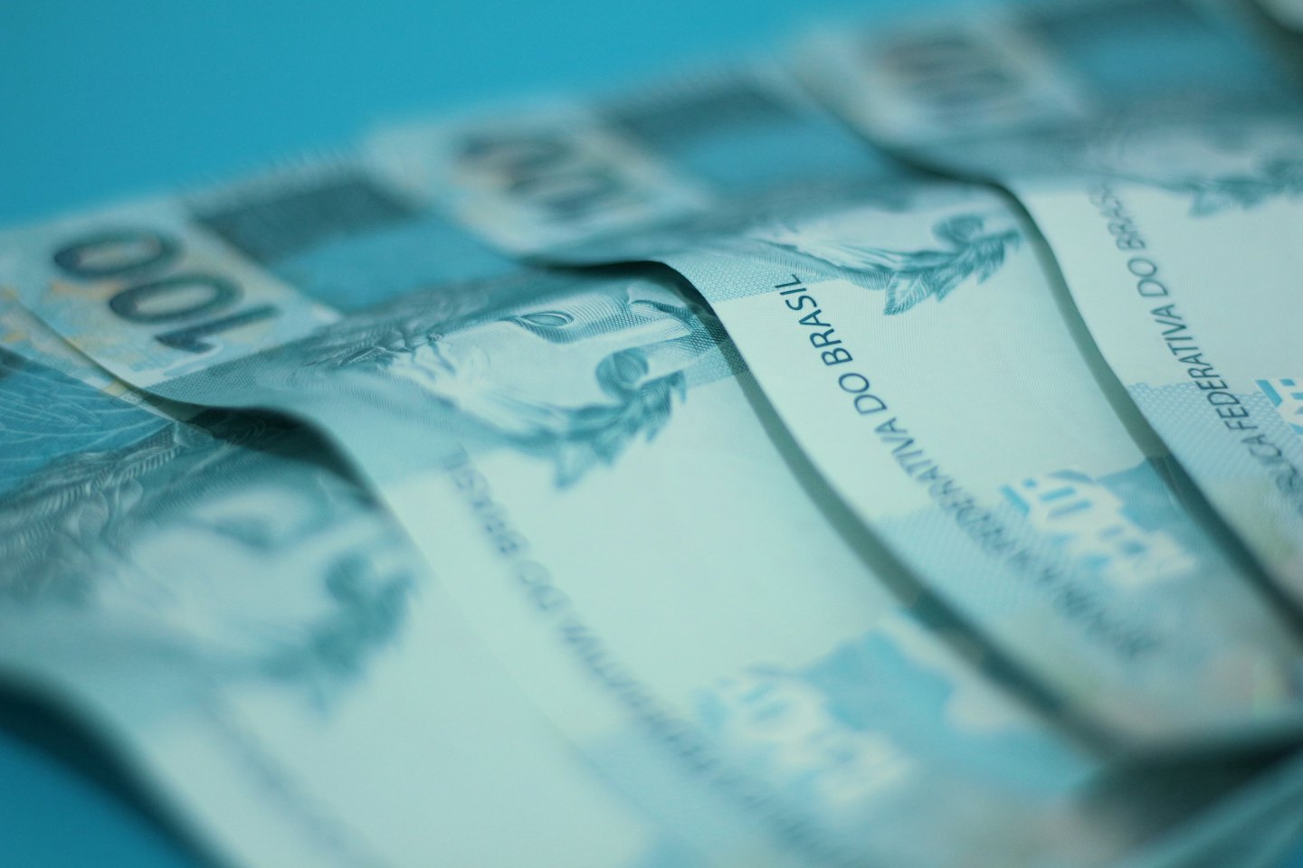 Blue Brazilian Real banknotes are fanned out on a surface.