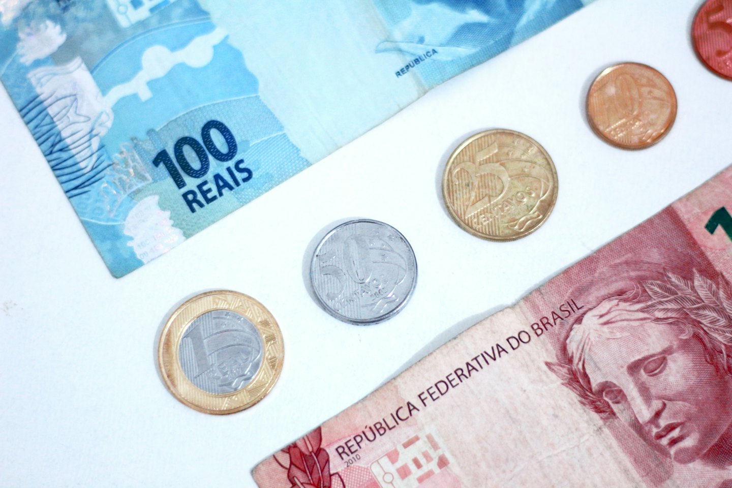 Brazilian Reais banknotes and coins arranged on a surface.